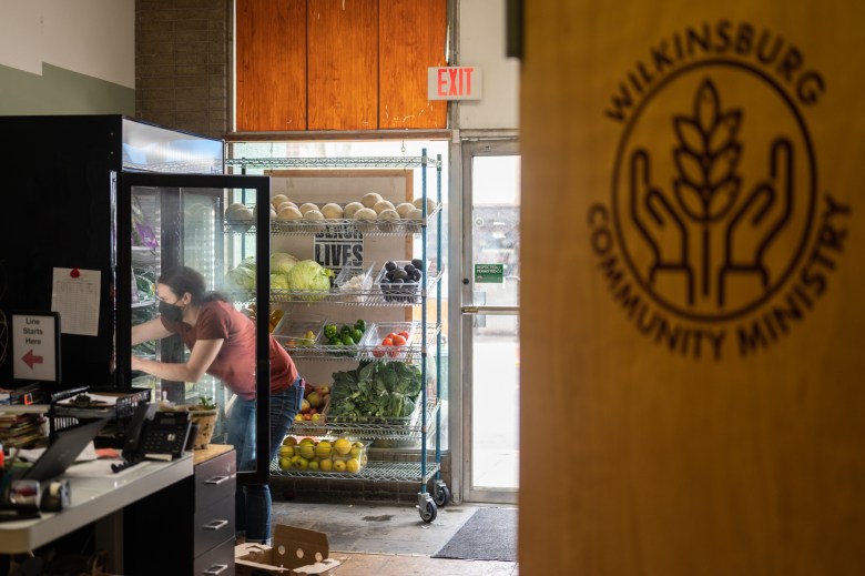 Melissa Wilson stocks a produce refrigerator in between guests at the Wilkinsburg Community Ministry food pantry.  Reed has seen an increase in people using the pantry since Snap benefits were cut back in March.  (Photo by Stephanie Strasburg/PublicSource)